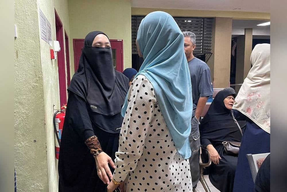 Sabrina (kiri) ketika menerima kehadiran sanak saudara di Unit Forensik Hospital Alor Gajah pada Jumaat.