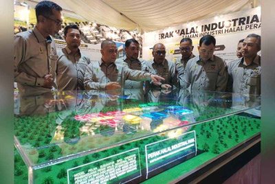 MENTERI besar Perak, Datuk Seri Saarani Mohamad (tiga dari kiri) melihat pelan pembangunan Perak HIP sempena majlis pecah tanah di Lekir pada Ogos tahun lalu. 