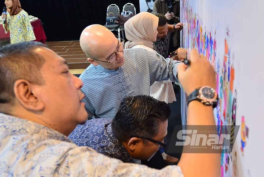 Nik Justin dan Ben Foo menandatangani mural 'Boleh' sebagai gimik pelancaran kempen di Dewan Auditorium Kumpulan Karangkraf pada Jumaat. Foto Sinar Harian - ASRIL ASWANDI SHUKOR