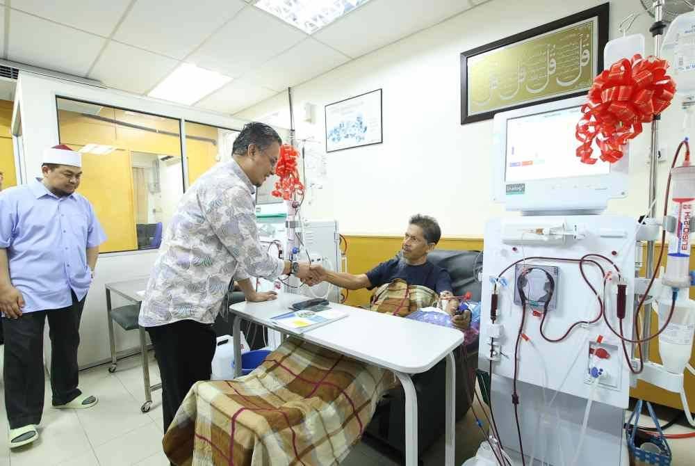 Mohamad menyantuni salah seorang pesakit di PHZ Bayan Baru pada Sabtu.