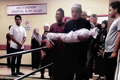 Mohd Fikry Amri membawa jenazah anaknya selepas dikafankan dan disolatkan di Unit Forensik Hospital Alor Gajah pada Jumaat.