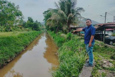 Mohd Izuan menunjukkan tali air di hadapan rumah penduduk di Taman Ilham yang menjadi punca banjir kilat.