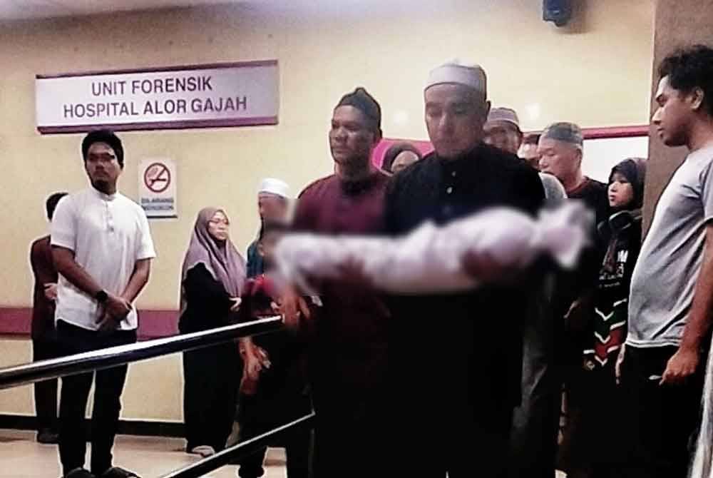 Bapa kepada bayi itu Mejar Ir TS Mohd Fikry Amri Abd Halim, 39, mengendong jenazah anaknya ketika keluar dari Unit Forensik Hospital Alor Gajah pada malam Jumaat.