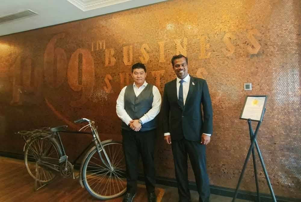 Sri Lingaswaran (kanan) bersama Pengurus Besar Restoran Cawan Mu, Christopher Chong di hadapan hiasan dinding menggunakan sepenuhnya kepingan syiling satu sen.