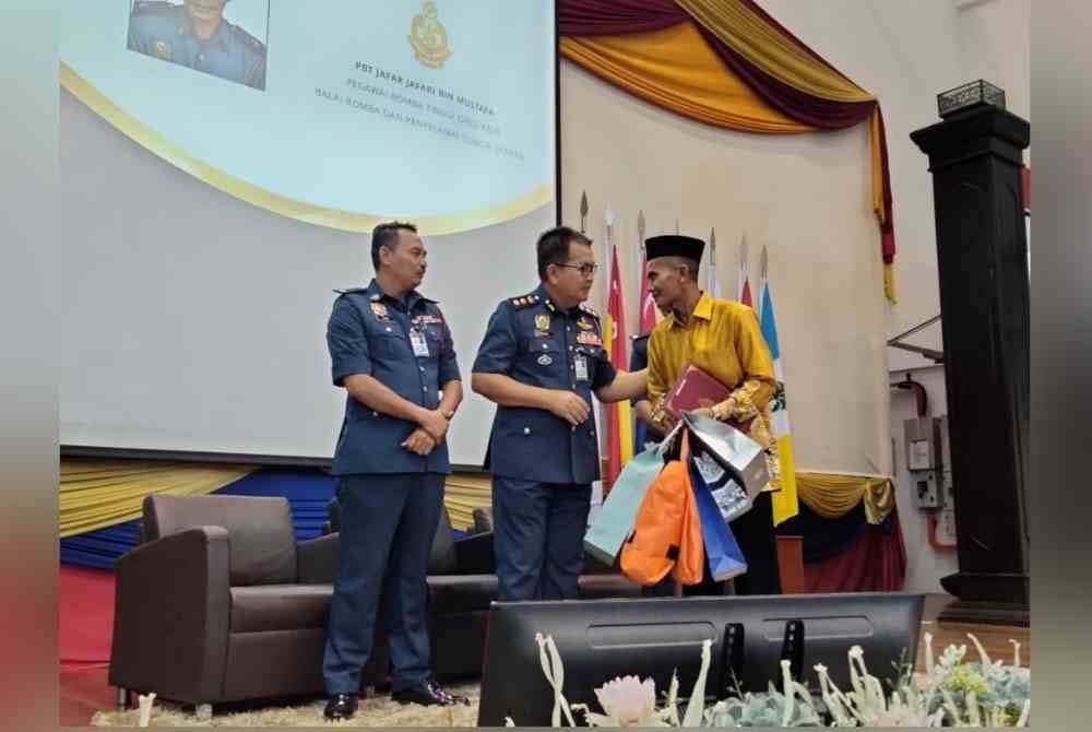 Zainal menyampaikan cenderahati kepada seorang pesara bomba ketika Majlis Perhimpunan Bulanan JBPM pada Ahad.