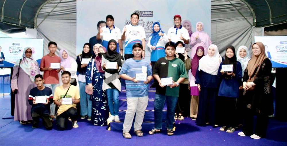 Sim Tze Tzin (belakang, dua dari kiri) dan Norliza (belakang, tiga dari kiri) bergambar bersama pelajar dan waris penerima sumbangan peranti.