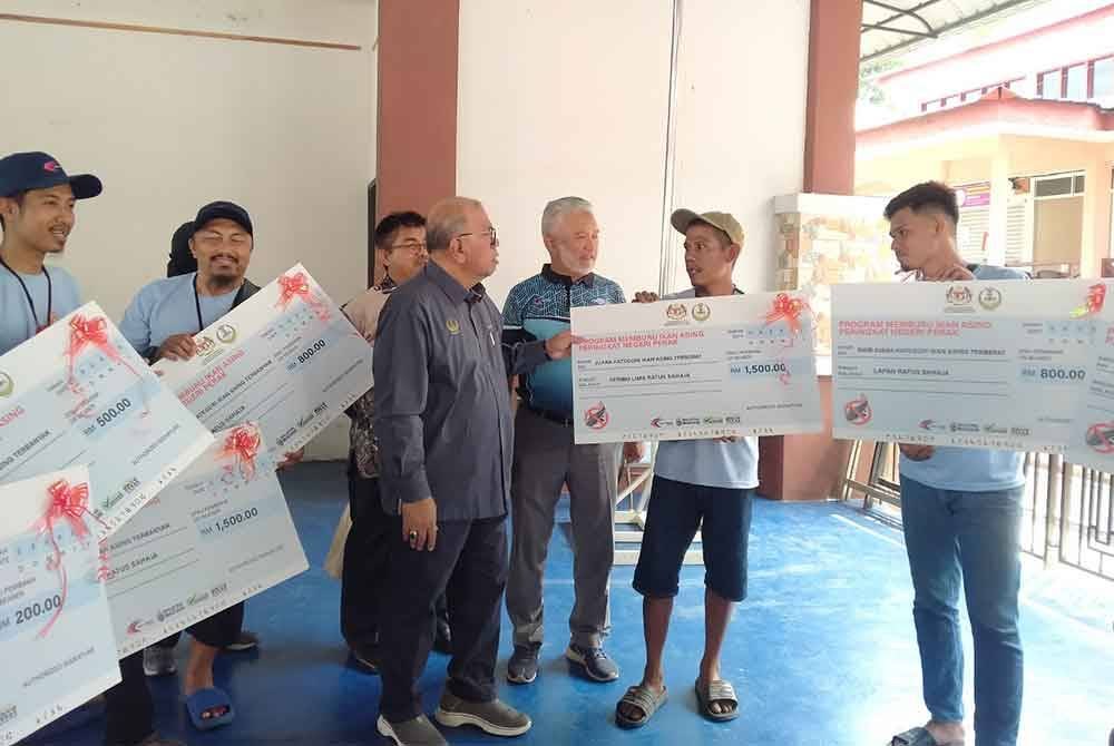 Mohd Zolkafly (empat dari kanan) bersama pemenang selepas menyempurnakan Majlis Penutup Program Memburu Ikan Asing di Dewan Terbuka Ngah Sagor, di sini pada Ahad.