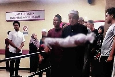 Bapa kepada bayi itu Mejar Ir TS Mohd Fikry Amri Abd Halim, 39, mengendong jenazah anaknya ketika keluar dari Unit Forensik Hospital Alor Gajah pada malam Jumaat.
