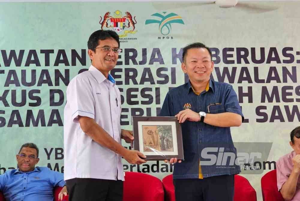 Ramle (kiri) menyerahkan cenderahati kepada Foong Hin pada Lawatan Kerja ke Beruas: Pemantauan Operasi Kawalan Ulat Bungkus dan Sesi Ramah Mesra bersama Pekebun Kecil Sawit di Beruas pada Isnin.