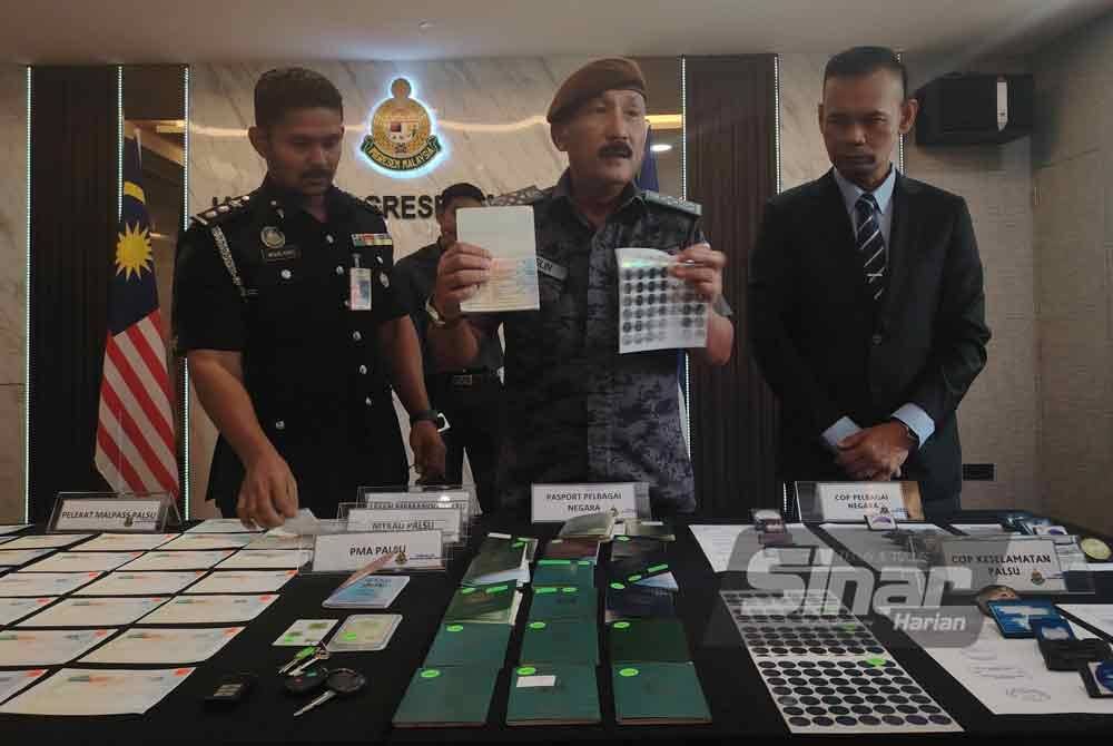 Ruslin (tengah) menunjukkan pelekat dan dokumen palsu yang dijual sindiket kepada warga asing.