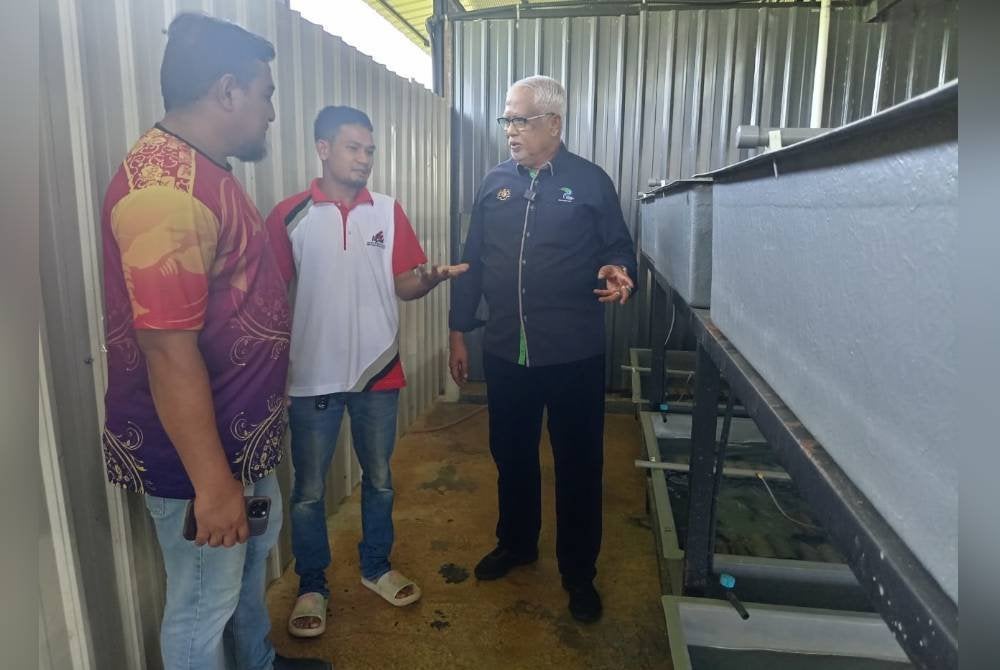Mahfuz (kanan) mendengar penerangan tentang kaedah penjagaan udang kara sambil ditemani Muhammad Firdaus (kiri) di Ladang Udang Kara Air Tawar Arbaah di Kampung Durian, di sini, pada Isnin.