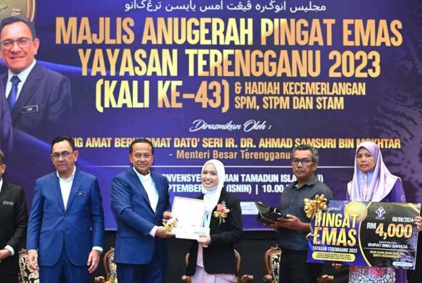 Mohd Azmi (kiri) mengiringi Ahmad Samsuri (dua dari kiri) menyampaikan anugerah kepada penerima Anugerah Pingat Emas Yayasan Terengganu, Nur Khalidah Adilah Mohammad.