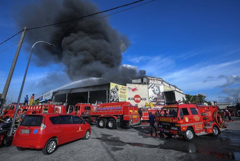 Anggota JBPM Kedah bertungkus-lumus memadamkan kebakaran gudang berkenaan. Foto Bernama