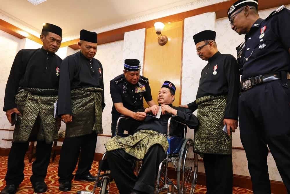 Azizi menyantuni seorang pesara polis, Haris Nawawi, 64, yang menerima Penganugerahan Pingat Jasa Pahlawan Negara (PJPN) Kontinjen Perak Tahun 2024 pada Khamis.