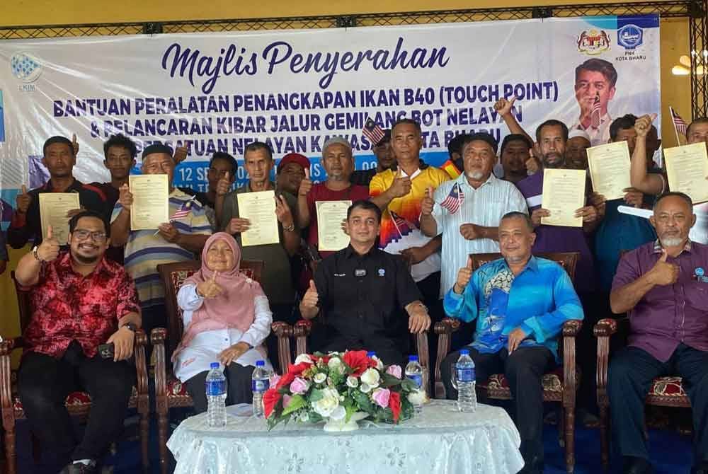 Muhammad Faiz (tengah,duduk) pada Majlis Penyerahan Bantuan Peralatan Penangkapan Ikan B40 dan Pelancaran Kibar Jalur Gemilang Bot Nelayan di LKIM Kuala Besar, Kota Bharu pada Khamis.
