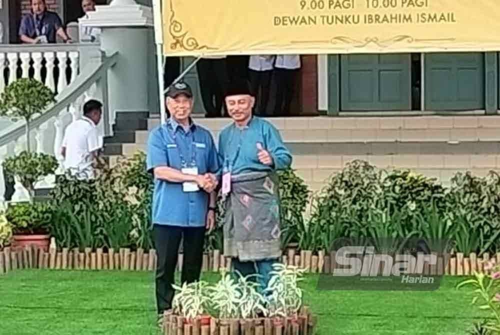 Mohd Haizan (kanan) bersalaman dengan Tan Sri Muhyiddin Yassin di Dewan Tunku Ibrahim Ismail pada Sabtu.