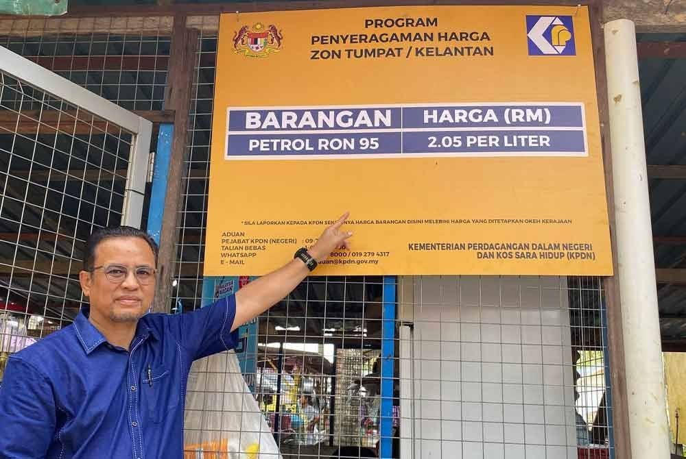 Azman menunjukkan harga semasa petrol di Kepulauan Tumpat semasa merasmikan Inisiatif Pendigitalan Sektor Peruncitan di Pasar Terapung dan Pelancaran Program Penyeragaman Harga Zon Tumpat di Pulau Sri Tanjong, Tumpat pada Sabtu.