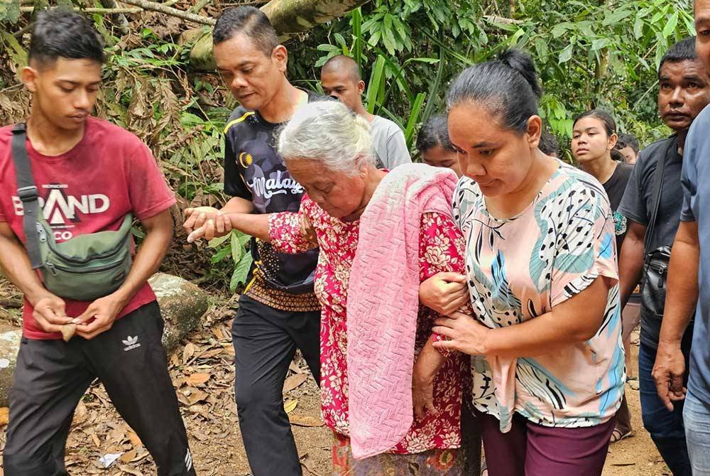 Anak mendiang memimpin ibu mereka, Krig (dua dari kanan) untuk ke Tanah Perkuburan Orang Asli Batu Berangkai, Kampar.