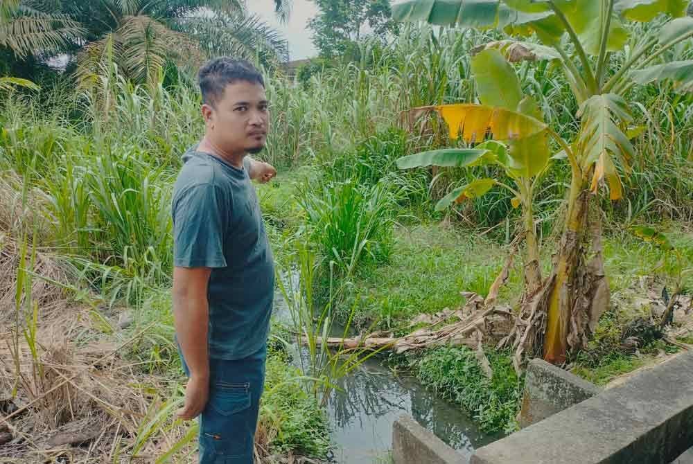 Mohamad Syafik menunjukkan keadaan longkang di belakang rumahnya di Lorong Dua, Kampung Baru, Kluang.