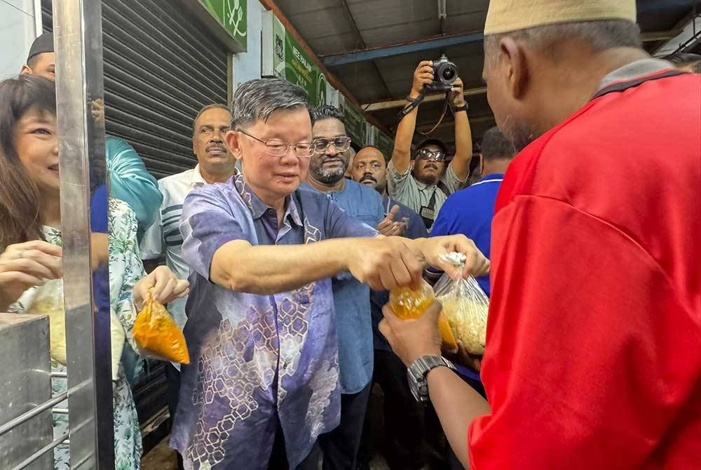 Kon Yeow mengagihkan makanan kepada orang ramai di Kompleks Padang Brown.