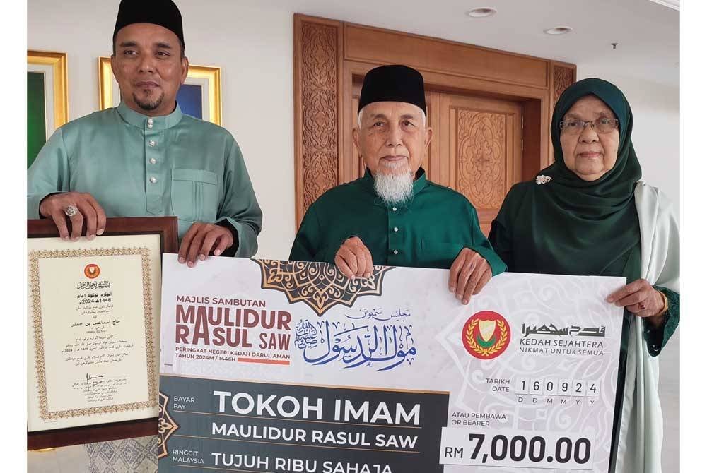 Ismail (tengah) bersama anak, Khairul Rijal (kiri) dan isteri, Embun Md Diah (kanan) bergambar bersama replika cek Tokoh Imam Maulidur Rasul diterimanya pada Majlis Sambutan Maulidur Rasul.