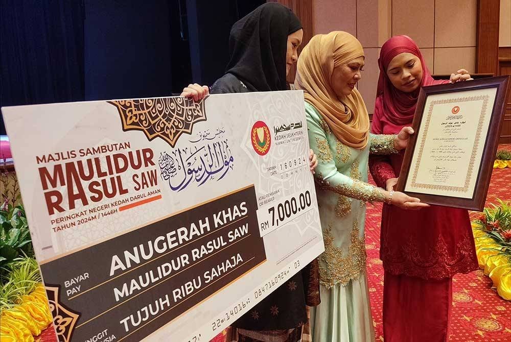 Rohani (tengah) ditemani anaknya, Nur Azryena (kiri) dan Siti Fairuz (kanan) melihat sijil penghargaan diterima Allahyarham Azraai pada Majlis Sambutan Maulidur Rasul Kedah.