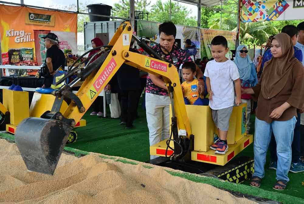 Ibu bapa membantu anak-anak mengendalikan 'mini excavator'.