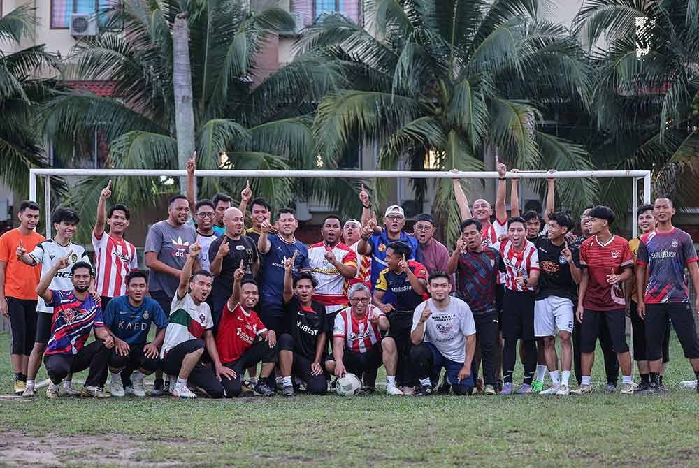 Tengku Zafrul bergambar bersama belia Kampung Melayu setelah meluangkan masa bermain bola sepak bersama mereka di sini, pada Isnin sempena kempen PRK DUN Mahkota. Foto Bernama