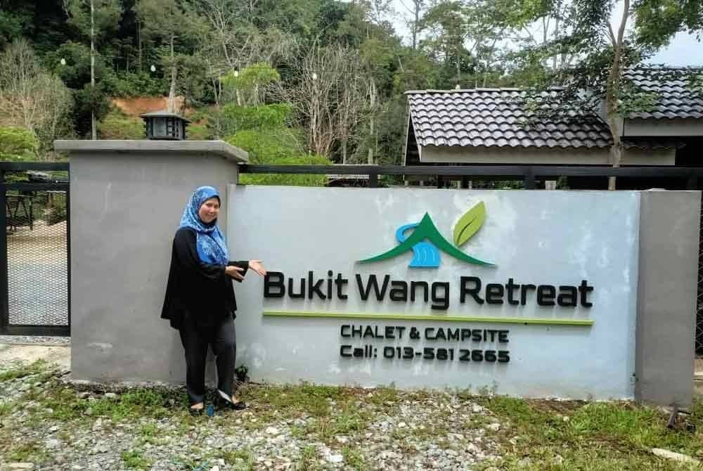 Nur Akmar bergambar di hadapan pintu masuk Bukit Wang Retreat Chalet & Campsite di Jalan Bukit Wang, Jitra.