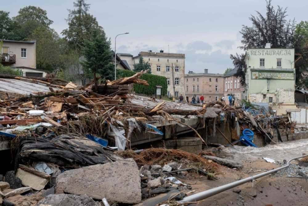 Penduduk tempatan berdiri di antara serpihan di jalan yang rosak akibat banjir di Ladek-Zdroj, selatan Poland. Foto AFP