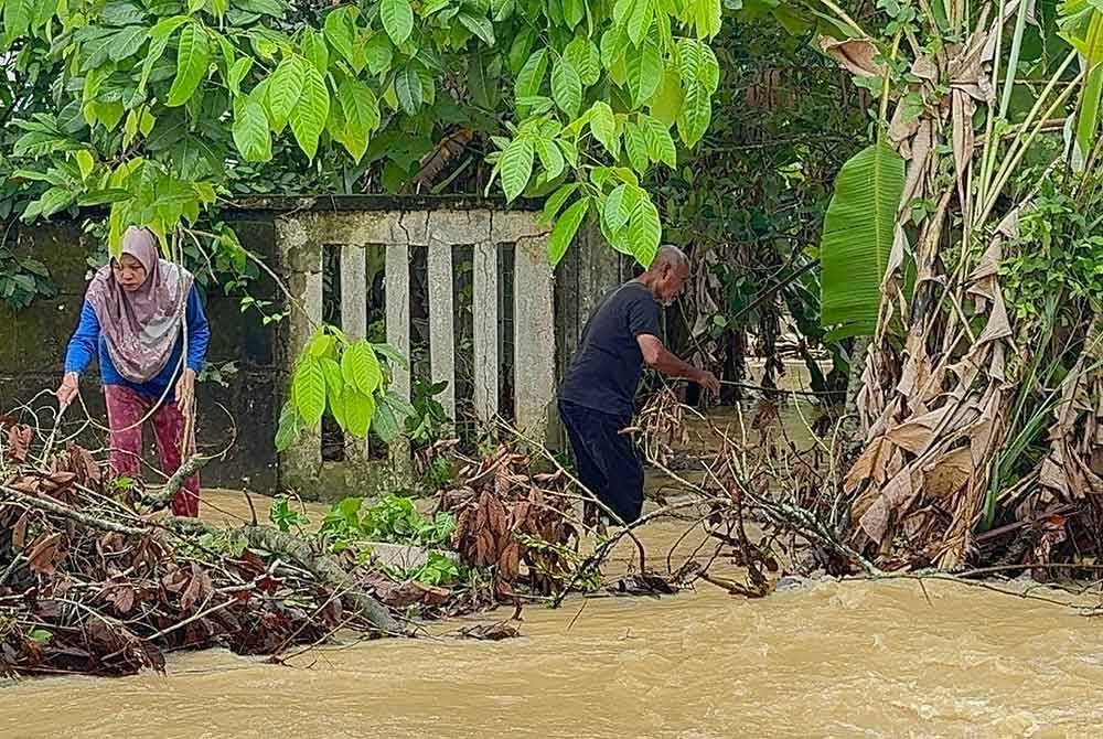 Penduduk kampung membersihkan serpihan kayu dan sampah yang hanyut dibawa arus.