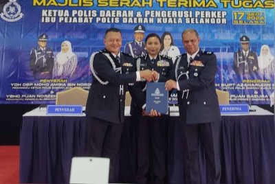 Mohd Ambia (kiri) menyerahkan dokumen serah tugas kepada Azaharudin (kanan) sambil disaksikan Sasikala di IPD Kuala Selangor di sini pada Selasa.