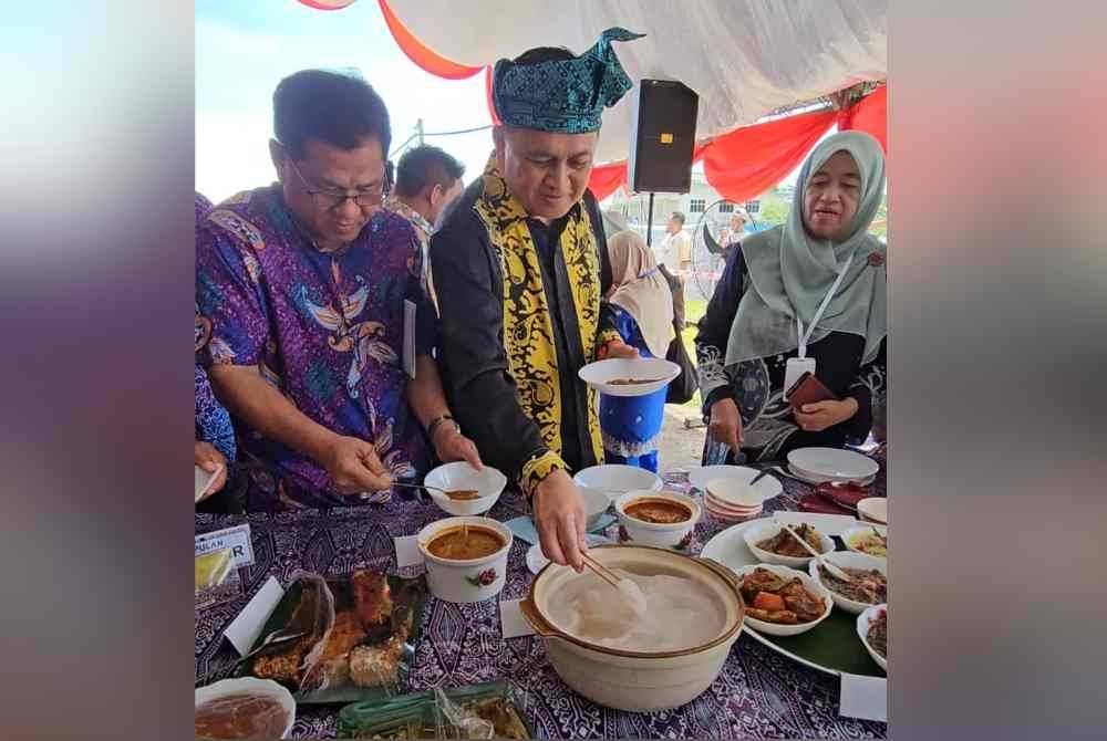 Mohd Arifin (tengah) ketika mencuba ambuyat yang dihidangkan pada Pesta Ambuyat di Membakut, Beaufort pada Isnin.