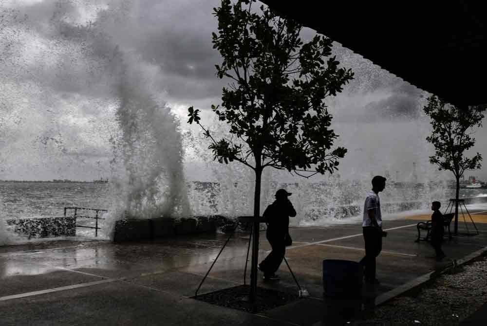 Pengunjung cuba mengelakkan diri daripada terkena percikan ombak ketika bersiar-siar di Padang Kota Lama pada Rabu.