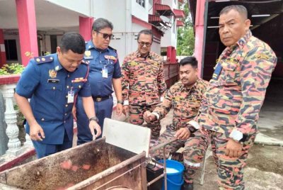 Mohd Azmi (kiri) dan ahli pasukan Rantau Mas menguji sistem pengesanan dan pemadaman kebakaran itu.