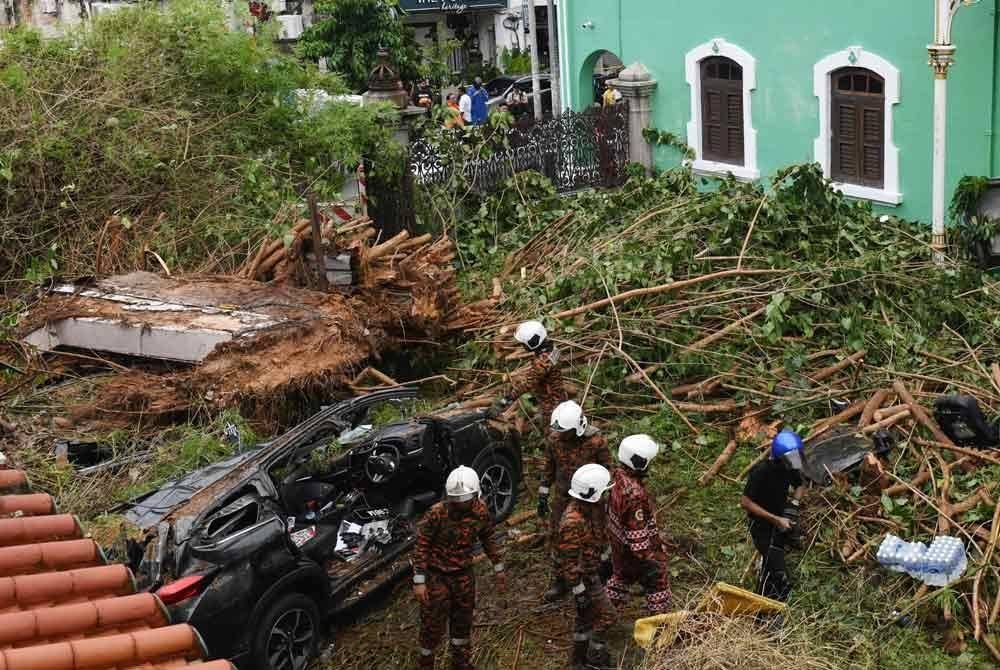 Keadaan kereta yang dihempap pokok tumbang di Lebuh Gereja pada Rabu. Foto Bernama