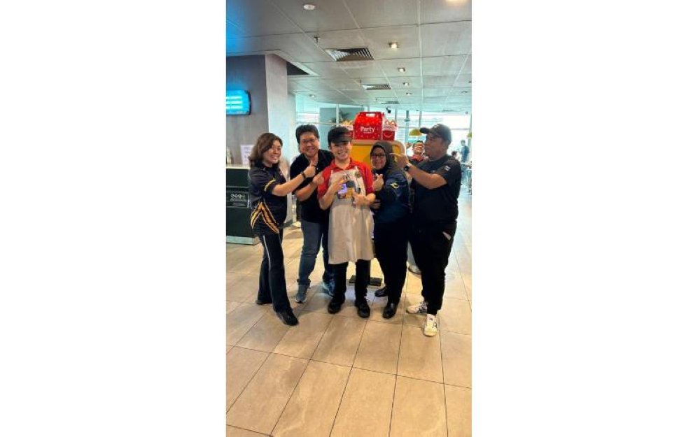 Jia Jun (tengah) gembira bekerja di McDonald’s.
