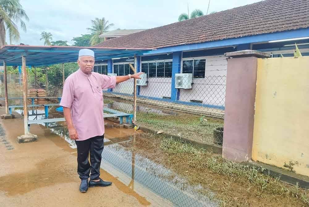 Zainol Abidin menunjukkan cadangan tembok yang akan dibina bagi mengelakkan limpahan air sungai masuk ke kawasan sekolah.