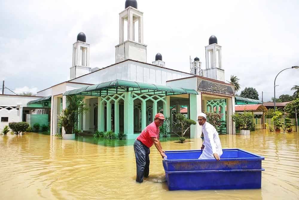 Jawatankuasa masjid menolak seorang jemaah uzur dalam tong ais yang disediakan untuk meredah air banjir di Masjid Tuan Hussein di Titi Gajah di sini.