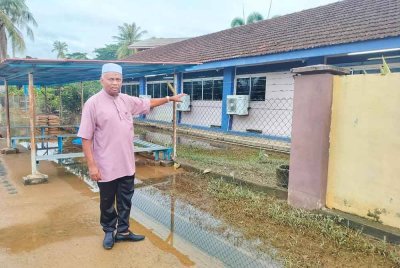Zainol Abidin menunjukkan cadangan tembok yang akan dibina bagi mengelakkan limpahan air sungai masuk ke kawasan sekolah.