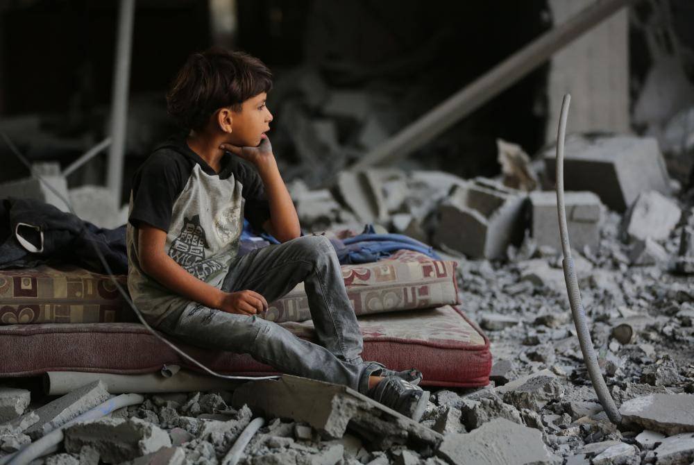 Seorang budak lelaki duduk di atas serpihan selepas pengeboman Israel di kem pelarian Nuseirat, tengah Semenanjung Gaza. Foto Xinhua