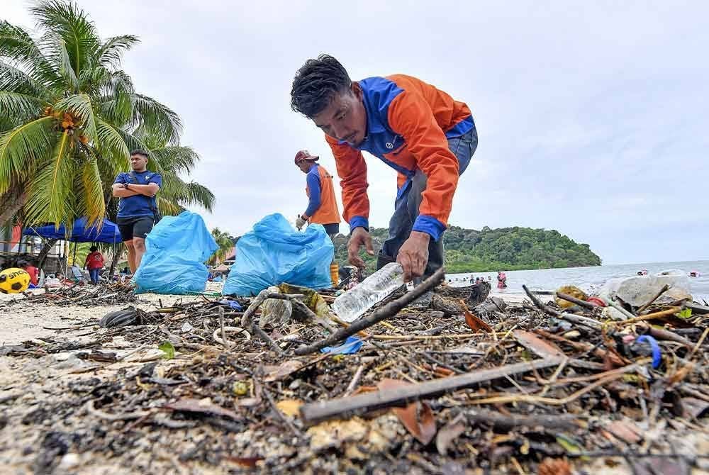 Petugas kebersihan turut berganding bahu membersihkan taburan sampah di sepanjang pesisiran pantai Tanjung Biru berikutan dibawa oleh air pasang besar di kawasan itu semalam. - Foto: Bernama