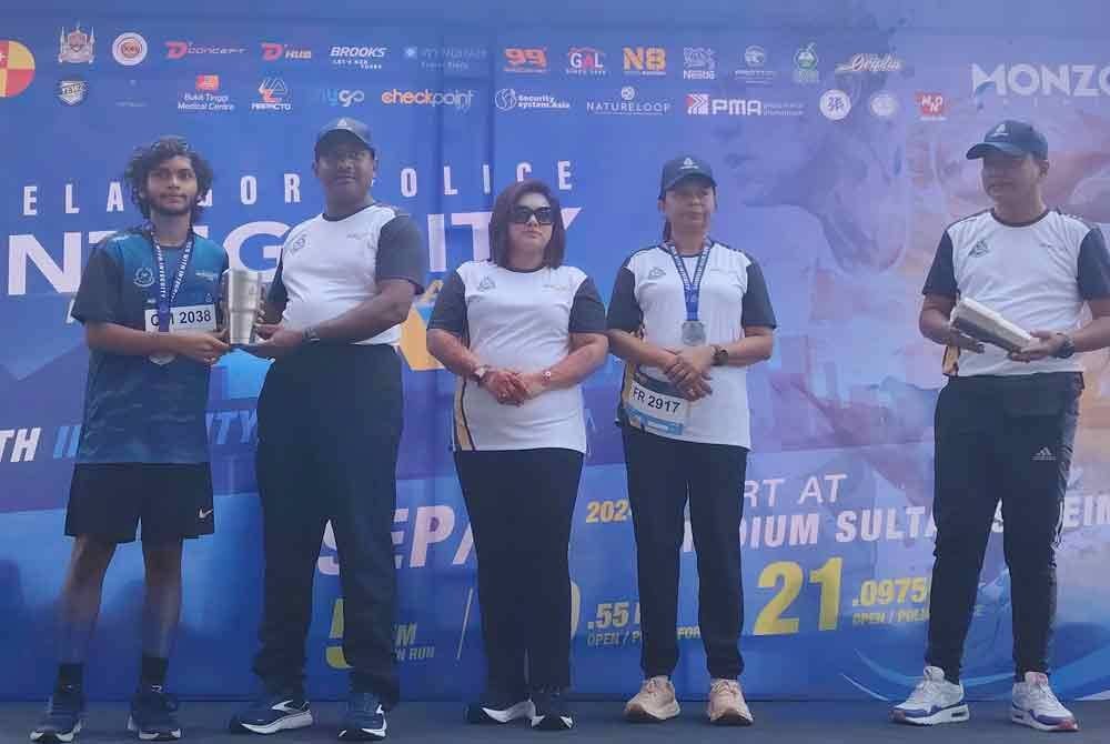 Hussein (dua dari kiri) menyampaikan hadiah kepada peserta Selangor Police Integrity Half Marathon 2024 di Stadium Sultan Suleiman, Klang pada Ahad.