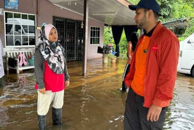 Muhammad Hamdi (kanan) ketika meninjau keadaan banjir di Permatang Pasir baru-baru ini.