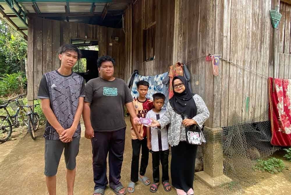 Muhamad Riduan (dua dari kiri) dan adik-adiknya semasa menerima kunjungan Hazelen Liana (kanan) ke rumah mereka di Kampung Chuchuh Puteri, Kuala Krai pada Ahad.