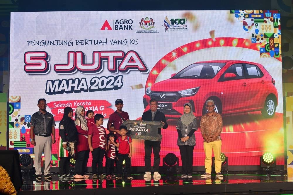 Azman dan keluarganya naik ke pentas selepas diumum sebagai pengunjung kelima juta memenangi kereta Perodua Axia yang ditaja Penaja Utama Agrobank.