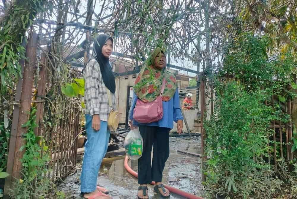 Salmah (kanan) dan Siti Nazila berada di hadapan rumah sewa mereka yang hangus terbakar di Tongkang Yard, Alor Setar pada Selasa.