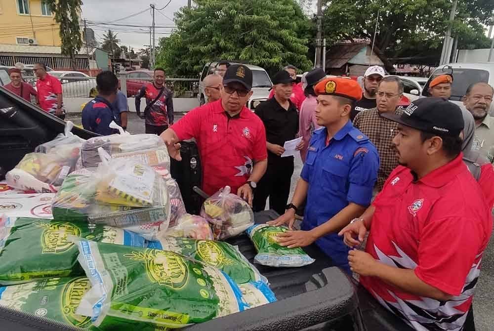 Ismasuhaimi (kiri) melihat bakul makanan yang akan diserahkan kepada mangsa banjir di Tongkang Yard, Alor Setar pada Selasa.