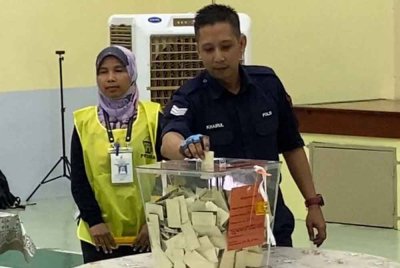 Mohd Khairul memasukkan kertas undi ke dalam peti undi.