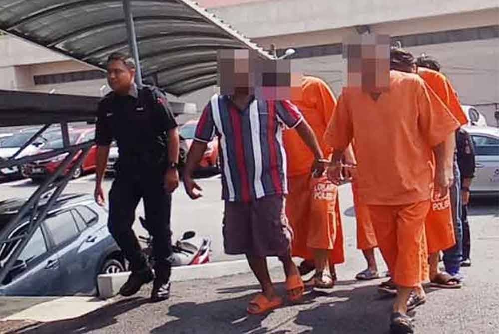 Tertuduh (dua dari kiri) diiringi anggota polis sebaik tiba di mahkamah.